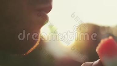 一个男人正在吃一个美味的红色成熟西瓜，背景模糊。 4K，3840x2160。 高清高清
